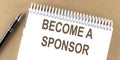 BECOME A SPONSOR text on a notepad with pen, business