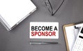 BECOME A SPONSOR Text written on the card with notebook and clipboard, grey background