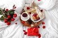 Tray with delicious breakfast, roses and present for Valentine's Day on soft bed Royalty Free Stock Photo