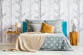 Bed against forest motif wallpaper