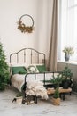 Bed with a beige plaid and green pillows, a Christmas wreath on the wall, a Christmas tree. New Year`s winter home interior decor Royalty Free Stock Photo