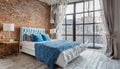 Bed with blue pillows against grid window. Loft interior design of modern bedroom with brick wall