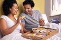 Bed, breakfast and couple with fruit for eating, nutrition and healthy with food in morning. Bedroom, man and woman with Royalty Free Stock Photo