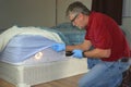 Bed bug infestation extermination service man inspecting infected mattress sheets and blanket bedding