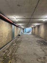 A bed and a chair belonging to a homeless person in a dirty walkway tunnel