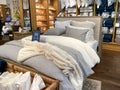 A bed with comforter, sheets, and pillows for sale at a Pottery Barn at an indoor mall in Orlando, Florida