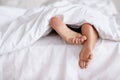 Bed, feet and person sleeping in home, relax and resting nap in sheets for health, calm and leisure in the morning. Foot