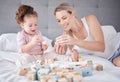 Bed, happy mother and baby with toys play together with alphabet education building blocks in home bedroom. Family love Royalty Free Stock Photo