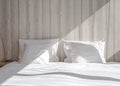 Bed made-up with clean white pillows and bed sheets in beauty room. Close-up. Lens flair in sunlight. Royalty Free Stock Photo