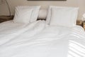 Bed maid-up with clean white pillows and bed sheets in beauty room. Close-up. Lens flair in sunlight. Royalty Free Stock Photo