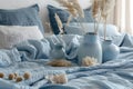 Bed with many pillows vases filled with dried grass on blue blanket. Concept Cozy Bedroom Decor,