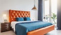 Bed with orange leather headboard and blue bedding. Art deco style interior design of modern bedroom Royalty Free Stock Photo