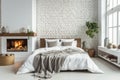 Bed with pillows and coverlet near fireplace against white brick wall. Loft, scandinavian interior design of modern bedroom. Royalty Free Stock Photo