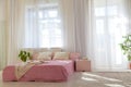 Bed with pink sheets in a white room with plants