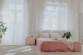 Bed with pink sheets in a white room with plants