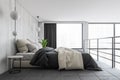 Bed on the second floor with linens, grey and white minimalist sleeping room Royalty Free Stock Photo