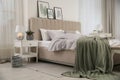 Bed with stylish grey linens near white wall in room Royalty Free Stock Photo