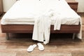Bed with white linens and white bathrobe with slippers in hotel Royalty Free Stock Photo