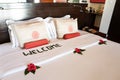 bed with white pillows and a coverlet, decorated with tropical flowers and an inscription - welcome. Theme of hotel service