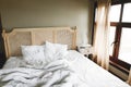 Bed with white sheets and vintage nightstand with decor at window in hotel room or provence home bedroom. Space for text.