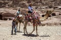 A Bedouin boy walks beside a group of tourists riding camels through the ancient ruins of Petra in Jordan. Royalty Free Stock Photo