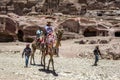 A Bedouin boy walks beside a group of tourists riding camels through the ancient ruins of Petra in Jordan. Royalty Free Stock Photo