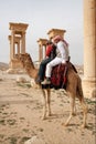 Bedouin boys riding camel in ancient city of Palmyra - Syria