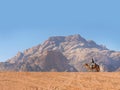 A Bedouin caravan riding a camel in the Desert of Wadi Rum, red and orange sand dune landscape, UNESCO World Heritage site, Royalty Free Stock Photo
