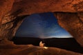 Bedouin in the Crimean cave Kachi-Kalyon is heated by the fire on the background of the starry sky