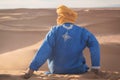 Bedouin nomad, Sahara desert, Morocco. Portrait of a Bedouin nomad with colorful turban and big smile sitting on sand dune. Royalty Free Stock Photo