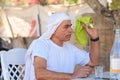 Bedouin senior tries to swat fly with towel. Old Arabic man in traditional clothes outdoor portrait. Royalty Free Stock Photo