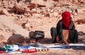Bedouin woman with covered face sits on sand in desert