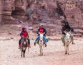 Bedouins on donkeys ride at the foot of the red rock in Petra near Wadi Musa city in Jordan