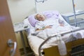 Bedridden female patient recovering after surgery in hospital care.