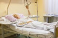 Bedridden female patient recovering after surgery in hospital care.