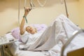 Bedridden female patient recovering after surgery in hospital care.