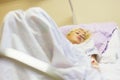 Bedridden female patient recovering after surgery in hospital care.