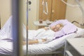 Bedridden female patient recovering after surgery in hospital care.