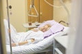 Bedridden female patient recovering after surgery in hospital care.