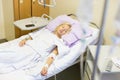 Bedridden female patient recovering after surgery in hospital care.