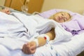 Bedridden female patient recovering after surgery in hospital care.