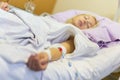 Bedridden female patient recovering after surgery in hospital care. Royalty Free Stock Photo