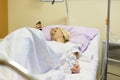 Bedridden female patient recovering after surgery in hospital care.