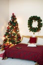 Bedroom with a bed and a Christmas tree in red and light colors Royalty Free Stock Photo