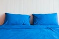 Bedroom with blue bed, blue two pillows, Blue duvet on the bed with wooden headboard. Royalty Free Stock Photo