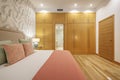 Bedroom with double bed and built-in wardrobe with wall panels with wooden doors and access to an en-suite bathroom Royalty Free Stock Photo