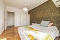 Bedroom with double bed with checkerboard slat parquet floor, white three-piece wardrobe and wallpapered walls Royalty Free Stock Photo