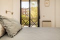 bedroom with double bed with headboard with gray cushions brown aluminum balcony overlooking a garden and decorative details on Royalty Free Stock Photo