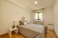 bedroom with double bed with headboard with gray cushions and round mirror with wooden frame and brown aluminum window with floral Royalty Free Stock Photo