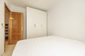 Bedroom with a double bed and a white three-section wardrobe and an oak door Royalty Free Stock Photo